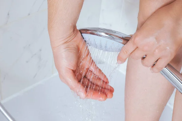 Mujer usando cabezal de ducha en el baño . — Foto de Stock