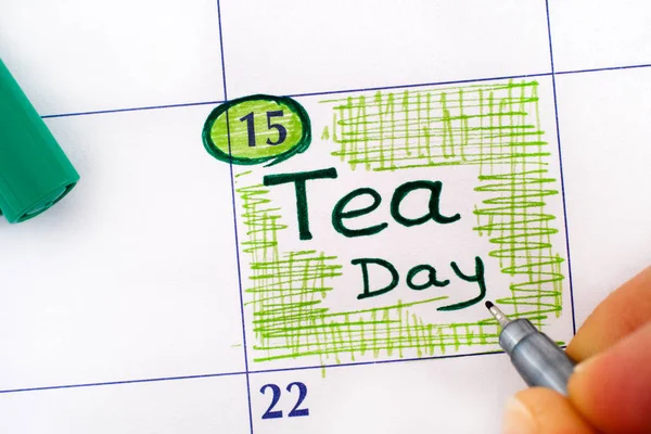 Dedos de mujer con pluma verde recordatorio de escritura Tea Day en calenda —  Fotos de Stock