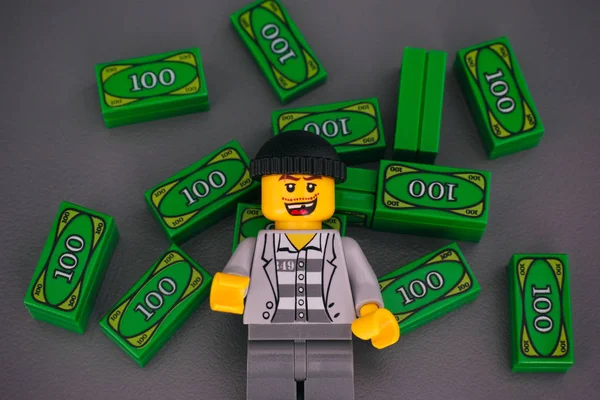 Лего преступник против Лего деньги кирпичи на сером фоне . — стоковое фото