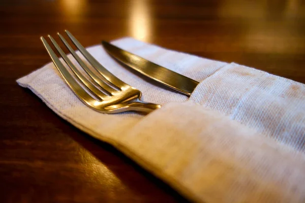 Table knife and fork in linen pockets on wooden table. — Stock Photo, Image