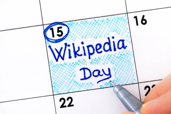 Vrouw vingers met pen schrijven herinnering Wikipedia Dag in calenda — Stockfoto