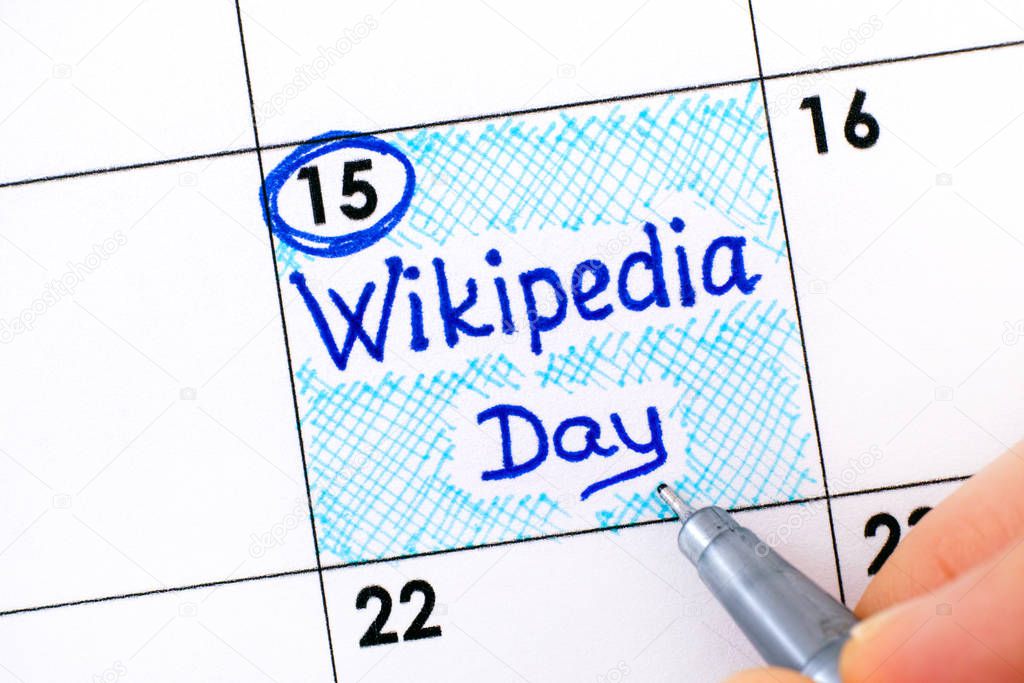 Woman fingers with pen writing reminder Wikipedia Day in calenda