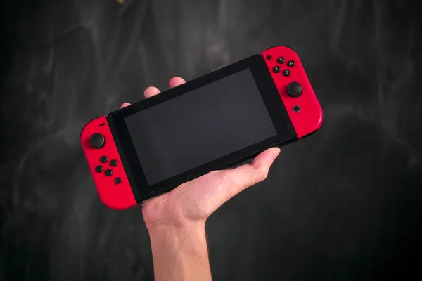 Mano de persona con consola de videojuegos Nintendo Switch contra blac — Foto de Stock