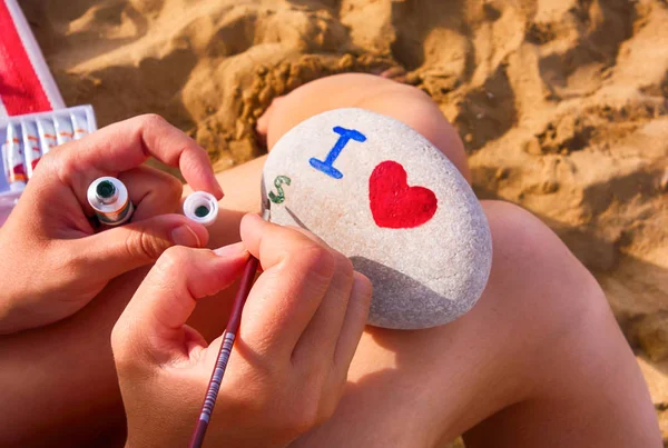 Donna sulla spiaggia sta disegnando su ciottoli - I heart, s . — Foto Stock
