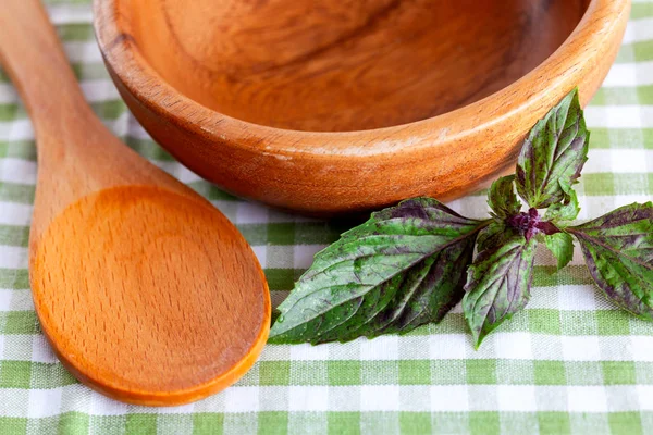 Table setting with wooden spoon, wooden bowl and basil on checke — Stock Photo, Image