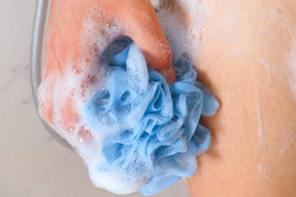 Mulher mão com esponja espumosa azul lavar seu corpo . — Fotografia de Stock