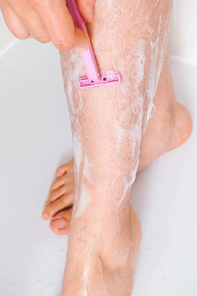 Woman shaving her legs in bathroom. Closeup. — Stock Photo, Image