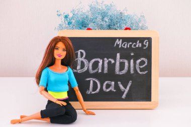 Tambov, Rusya Federasyonu - 24 Şubat 2020 Kahverengi saçlı Barbie bebek 9 Mart 'ta Barbie Günü sözleriyle tahtaya oturdu. Stüdyo çekimi.