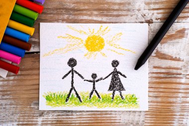 Çocuk eli çiziyor Aile - Anne, baba ve oğul Ahşap arka planda balmumu boya kalemleriyle.