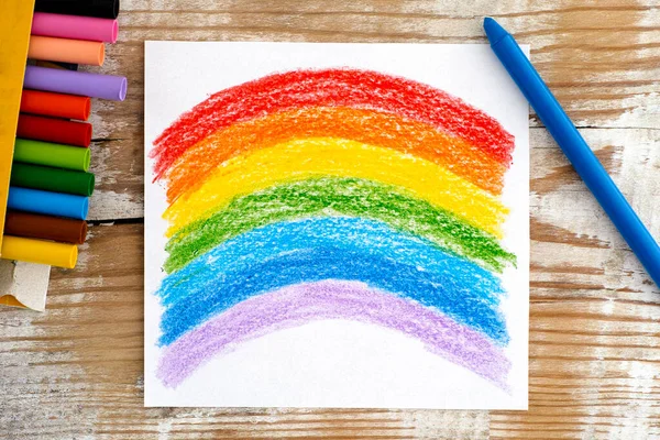 Hand drawing Rainbow with wax crayons. Wooden background.