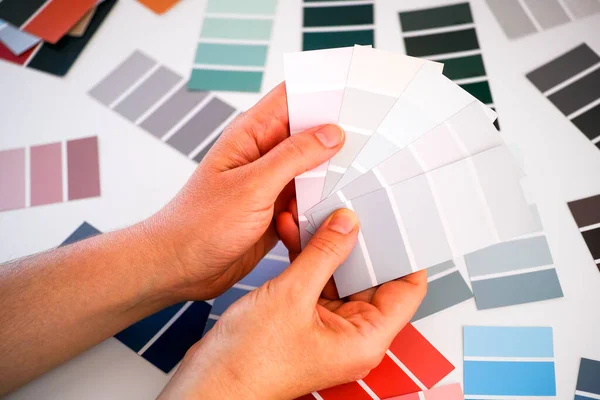 Woman hands choosing colour in color swatches. Closeup.