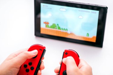 Tambov, Rusya Federasyonu - 27 Aralık 2019 Kid ve Joy-Cons Nintendo Switch konsolunda Super Mario Maker 2 video oyunu oynuyorlar. Beyaz arkaplan.