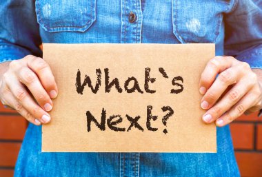 Kadın elleri kartondan bir parça tutuyor. Duvarın arkasında sırada ne var?.