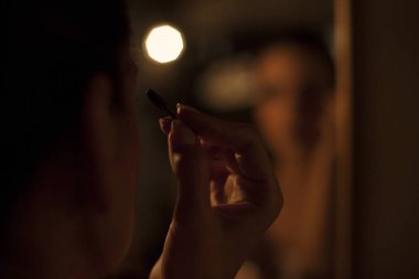 Romantik bir ışıkta makyaj yapan şehvetli bir kadın.