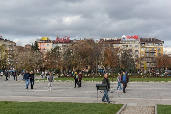 Sofia, Bulgaristan-12 Kasım 2017: Sofya Ulusal Kültür Sarayı önünde park insanlar yürürken