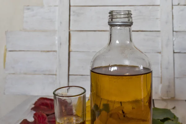 Fles en glazen cognac op de achtergrond van herfstbladeren — Stockfoto