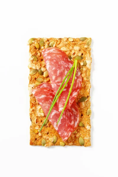 Pumpkin seed cracker with dry salami — Stock Photo, Image