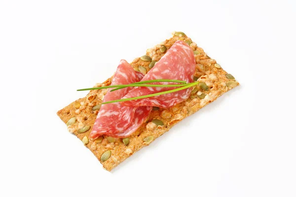 Pumpkin seed cracker with dry salami — Stock Photo, Image