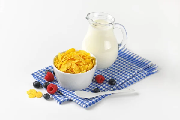 Kom met cornflakes en kruik van melk — Stockfoto