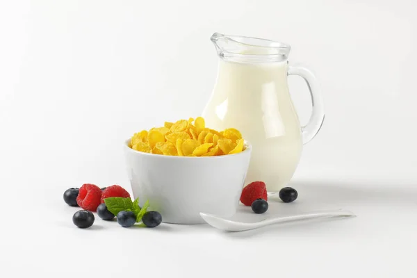 Kom met cornflakes en kruik van melk — Stockfoto