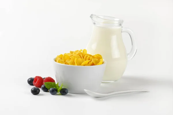 Tazón de hojuelas de maíz y jarra de leche — Foto de Stock