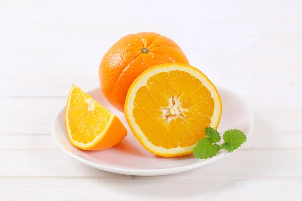 Целые и нарезанные апельсины — стоковое фото