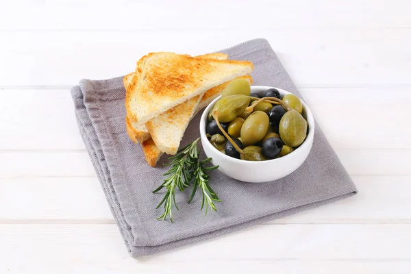 Aceitunas en escabeche, alcaparras y bayas de alcaparra con tostadas — Foto de Stock