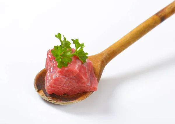 Pedaço de carne crua em colher de madeira — Fotografia de Stock