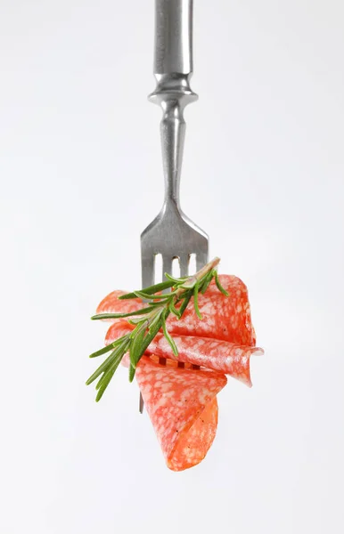 Tunna salamiskivor och rosmarin på gaffel — Stockfoto