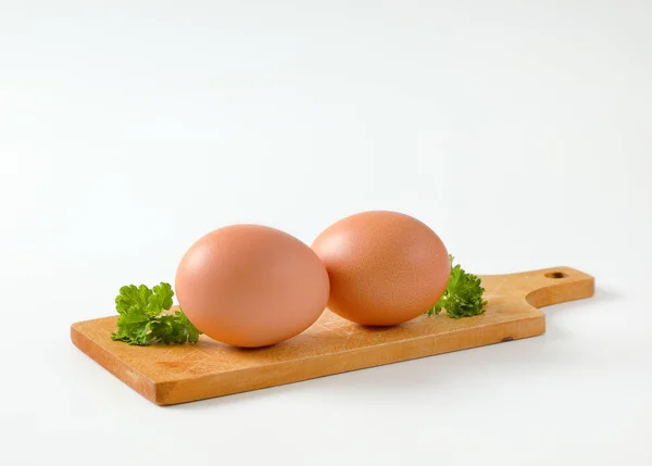 Twee bruine eieren op snijplank — Stockfoto