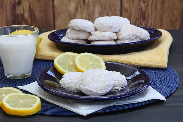 Lemon cookies with powdered sugar with lemons and a glass of mil — Stock Photo, Image