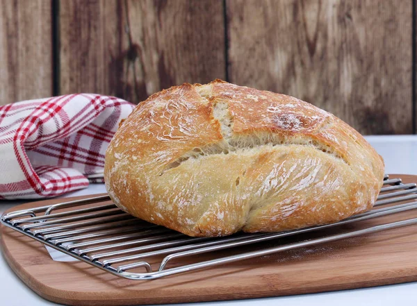 Une miche de pain artisanal frais cuit sur une grille de refroidissement . — Photo
