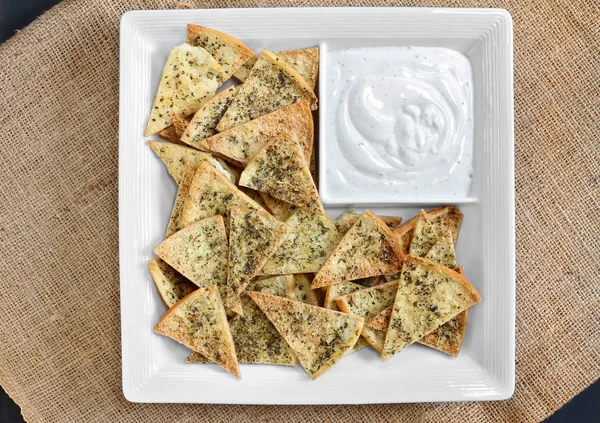 Bovenaanzicht van zelfgemaakte kruidige pita chips en dip. — Stockfoto