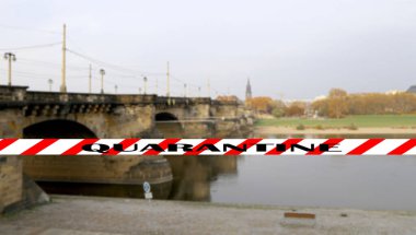 Dresden, Almanya 'da Coronavirus. Elbe nehri üzerindeki köprü manzarası. Bulanık bir arka planda karantina işareti. COVID salgını kavramı ve Avrupa 'da seyahat.