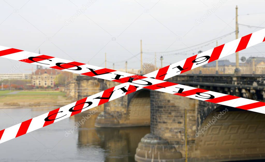 Coronavirus in Dresden, Germany. View of bridge over Elbe river. Covid-19 sign on a blurred background. Concept of COVID pandemic and travel in Europe.