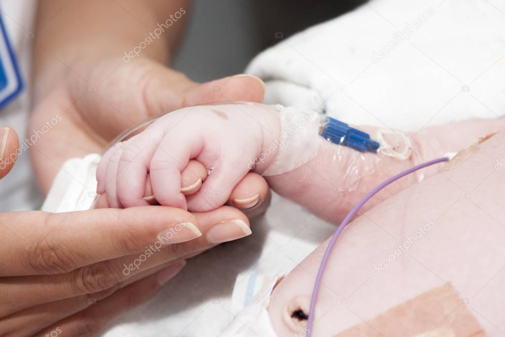 Portrait of newborn baby and hand inside incubator