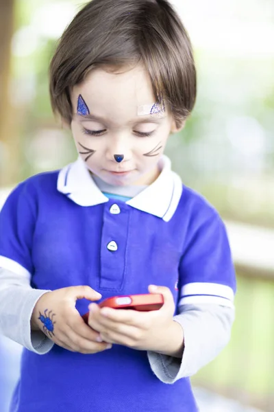 Schöner Junge Mit Geschminktem Gesicht Der Mit Dem Handy Spielt — Stockfoto