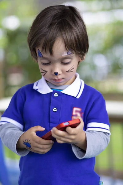 Schöner Junge Mit Geschminktem Gesicht Der Mit Dem Handy Spielt — Stockfoto