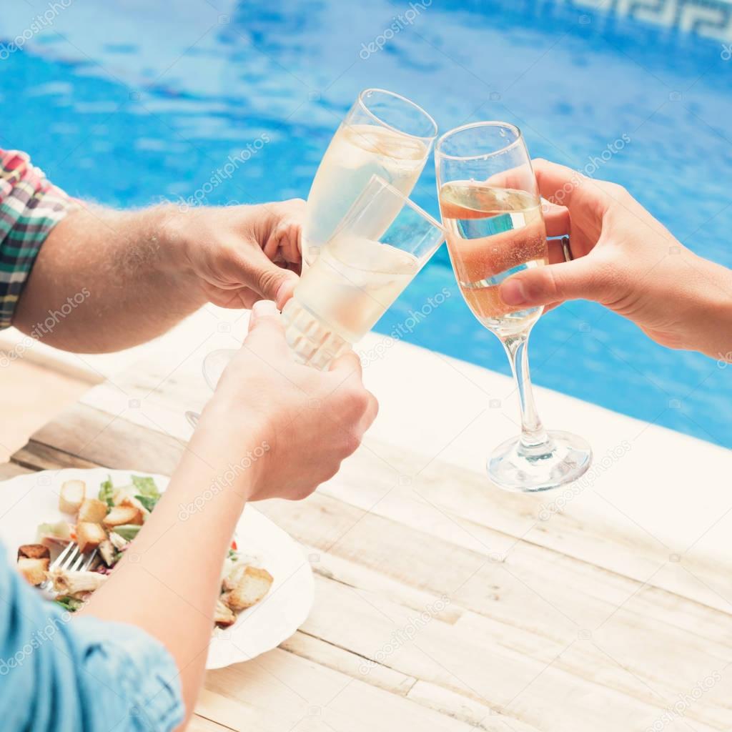 Friends having wine at party by swimming pool