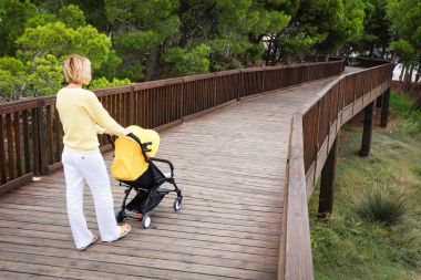 Genç kadın bir bebek arabası ahşap köprü üzerinde geziniyor