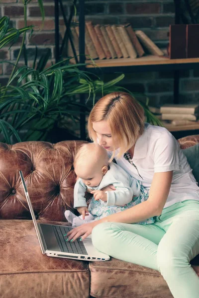 Young mother working at home with baby girl