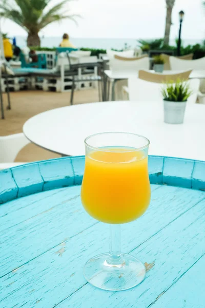 Sklenice pomerančové šťávy na modré retro stolku v kavárně — Stock fotografie