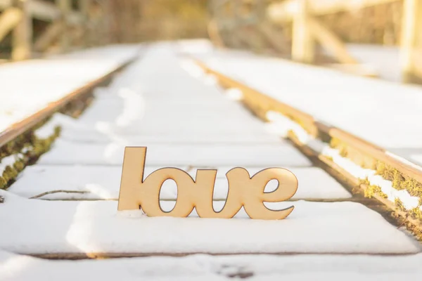 Segno di amore in legno su vecchie rotaie nella neve — Foto Stock