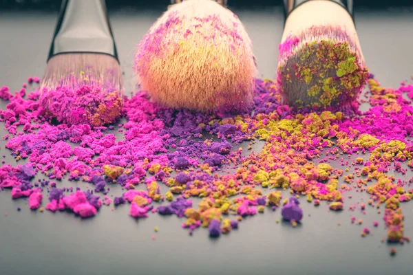 Make-up brushes on colorful powder — Stock Photo, Image