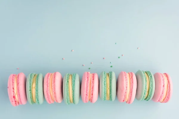 Zoete kleurrijke bitterkoekjes in rij op blauwe achtergrond — Stockfoto