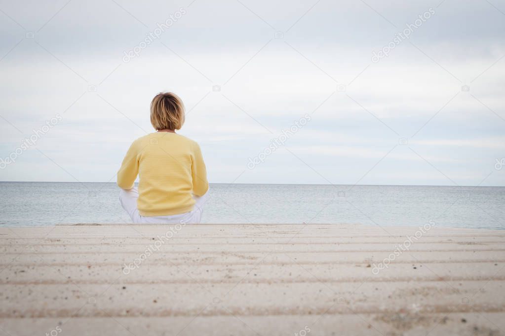 Woman looking through the sea while sitting on beach