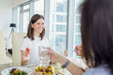 Mutlu gülümseyen kadın arkadaşlarıyla akşam yemeği. Birlikte akşam yemeği keyfi mutlu kadın