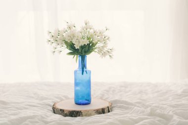 Mavi cam şişe içinde beyaz çiçekler