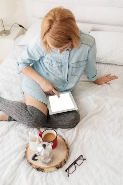Woman with coffee sitting on bed — Stock Photo, Image