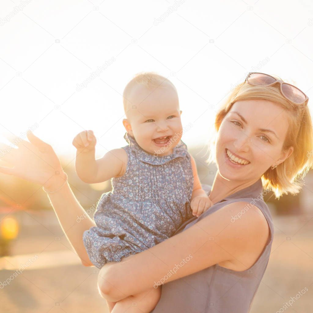 Young happy woman with daughter on beach